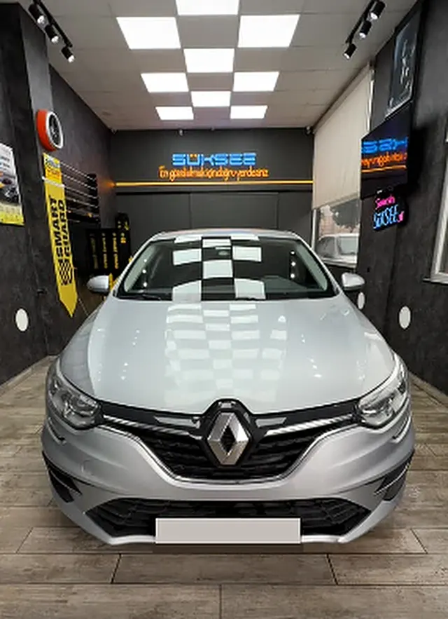 Gri Renault Mégane, Smart Guard afişinin önünde